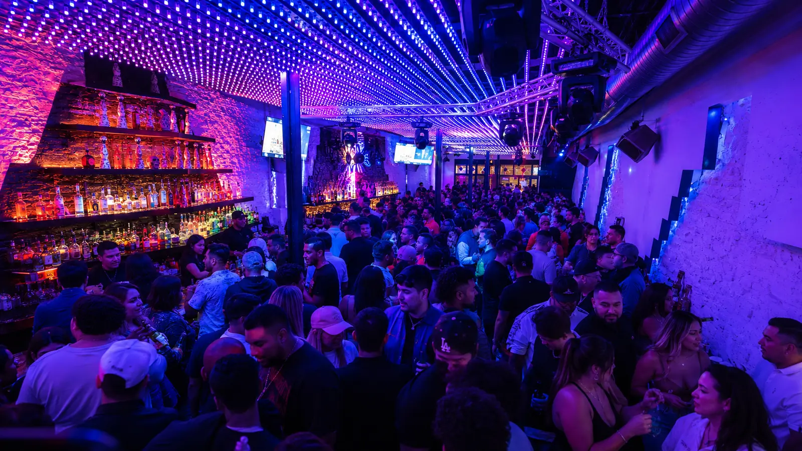 Packed Austin nightclub dance floor under purple and blue LED lights